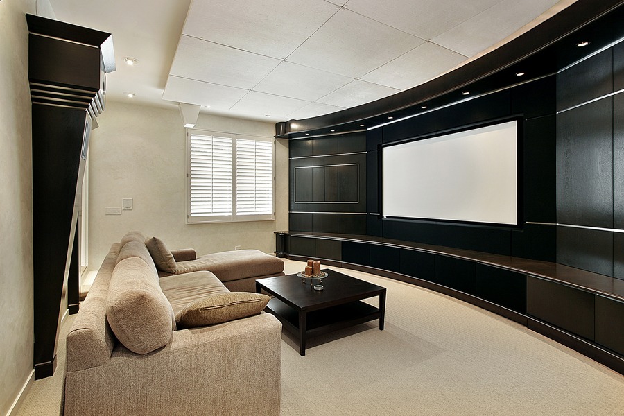 Contemporary home theater with a curved black entertainment wall, a plush beige sectional sofa, and a dark coffee table, creating a stylish relaxation space.