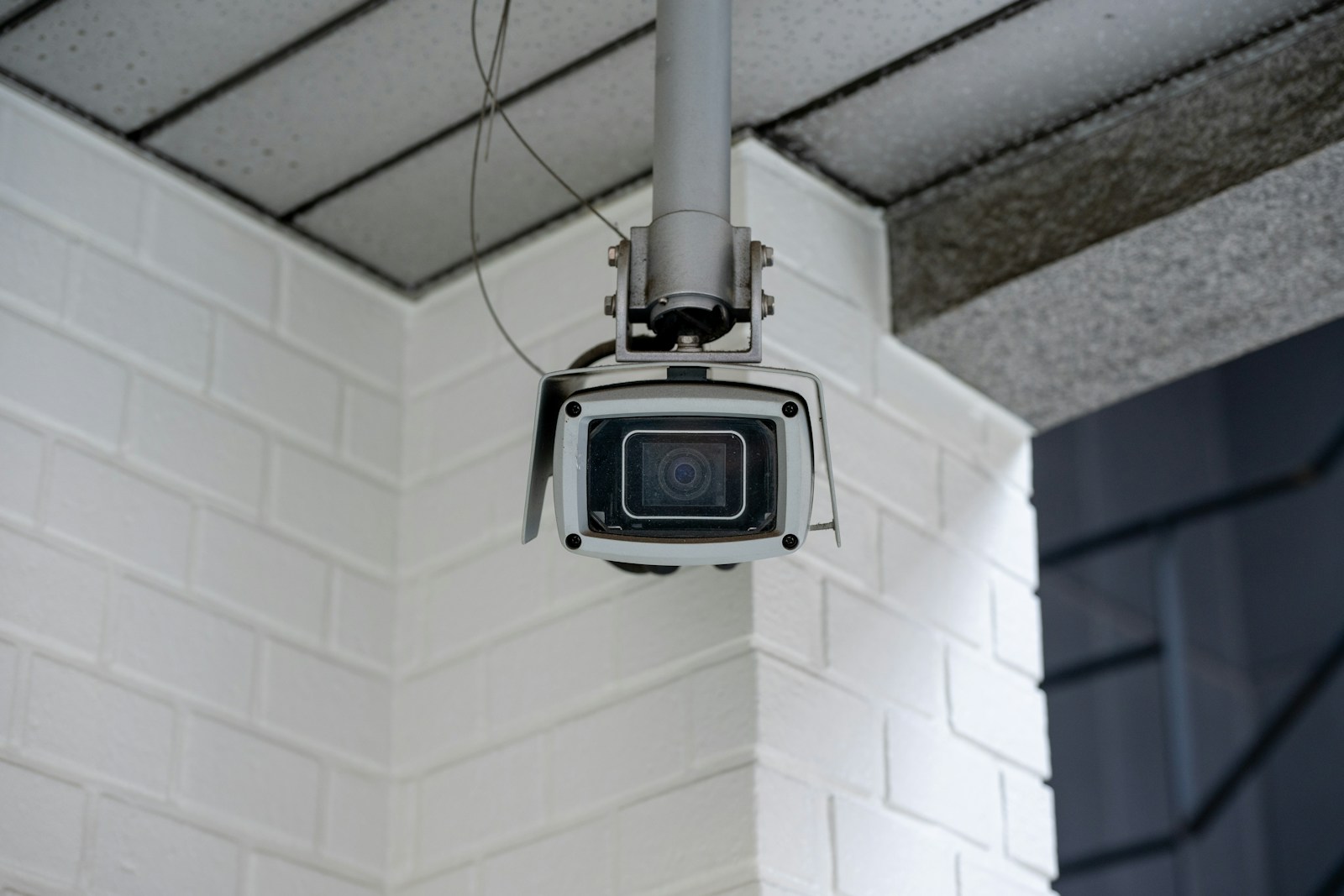 Security camera mounted on a white brick wall.